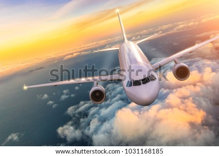 Commercial airplane jetliner flying above clouds in beautiful sunset light. Concept of travel and business.