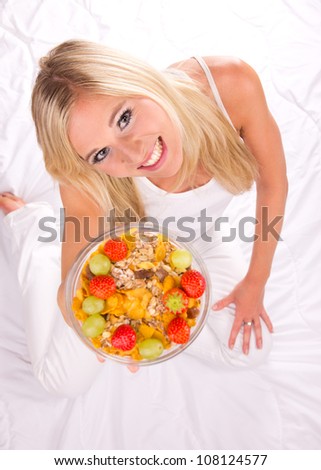 Attractive girl holding healthy bowl of cereals. Shot from upper view. Focused on eyes