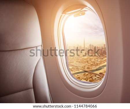 Airplane interior with window view of Dubai city, UAE. Concept of travel and air transportation