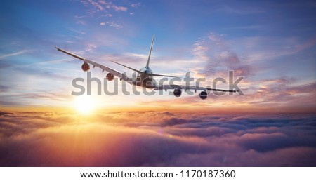 Huge two-storey passengers commercial airplane flying above clouds in sunset light. Concept of fast travel, holidays and business.