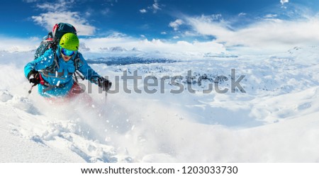 Alpine freeride skier skiing downhill with powder snow explosion. Winter sports and leasure activities