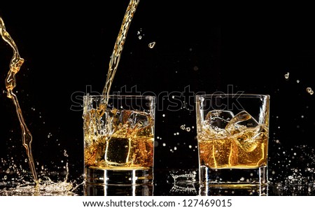 Alcohol drinks with splashes, isolated on black background