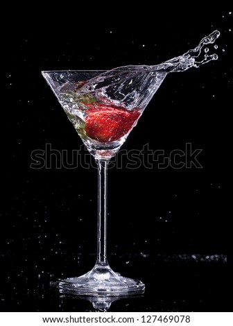 Martini drink splashing out of glass, isolated on black background