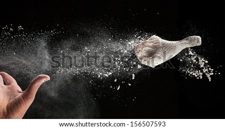 Chicken leg with flour in freeze motion, isolated on black background