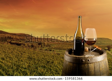 Red wine on wooden keg with vineyard on background