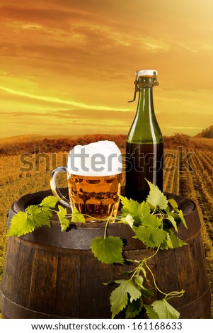 Beer keg with glass of beer on rural countryside background