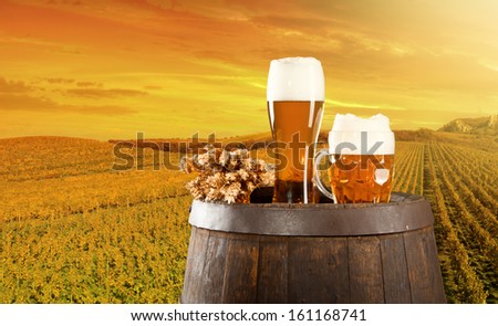 Beer keg with glasses of beer on rural countryside background