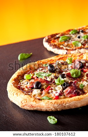 Home made fresh italian pizza with vegetable. Served on black stone surface. Orange background