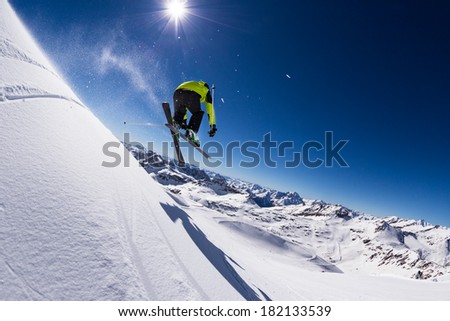 Alpine skier in high jump, blue sky on background