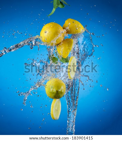 Studio shot of fresh lemons with water splash on blue background