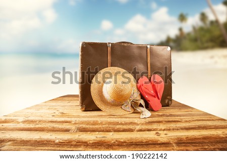 Concept of summer travelling with old suitcase and accessories. Blur beach on background