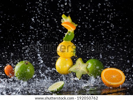 Isolated shot of falling citrus fruit in water splashes on black background