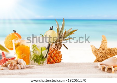 Exotic summer drinks with sea shells and stars, blur sandy beach on background