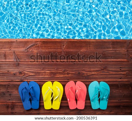 Concept of summer sandals on wood with blue water as background