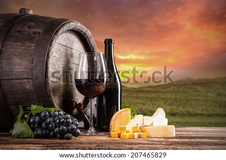 Wine still life on wooden keg with vineyard on background