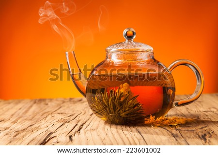 Teapot with blooming tea on wooden planks