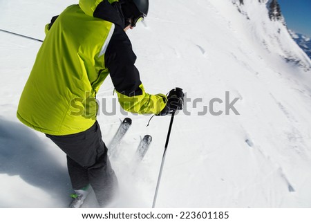Alpine skier skiing downhill, blue sky on background
