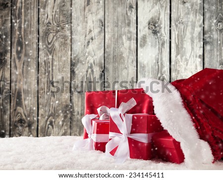 Santa Claus bag full of gifts on snow. Wooden planks as background