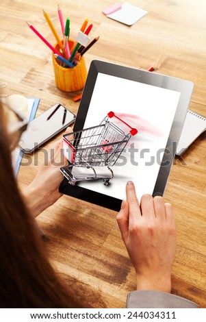 Woman working with tablet placed on wooden desk. Concept of internet shopping
