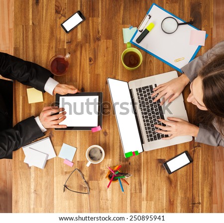 Man and woman working on laptop and tablet. Shot from above view