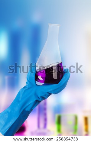 Hand holding chemical liquid in glass flask in laboratory