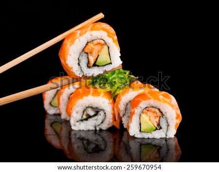 Delicious sushi rolls served on black table with chopsticks
