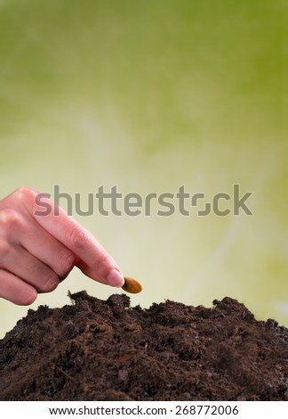 Woman hand seeding seed into pile of soil