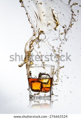 Whiskey ice drink with splash on gray background