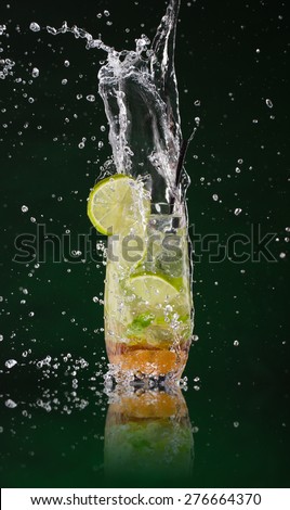Fresh mojito drink with ice cubes and splashes on black background