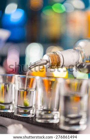 Barman pouring hard spirit into glasses in detail