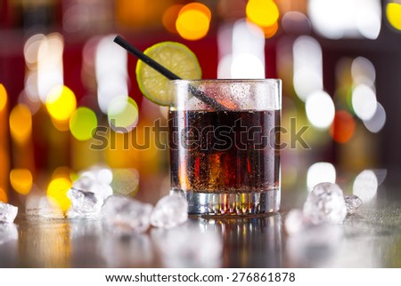 Glass of cola drink on bar counter with ice cubes
