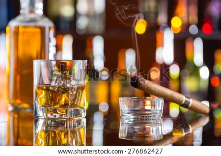 Whiskey drink with smoking cigar on bar counter
