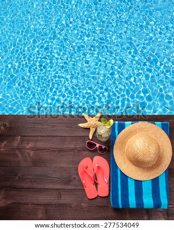 Swimming accessories on wooden mole placed next to water surface of pool. Shot from bird-eye perspective