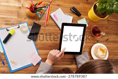 Young woman working with tablet placed on wooden desk with blank screen for text. Shot from aerial view