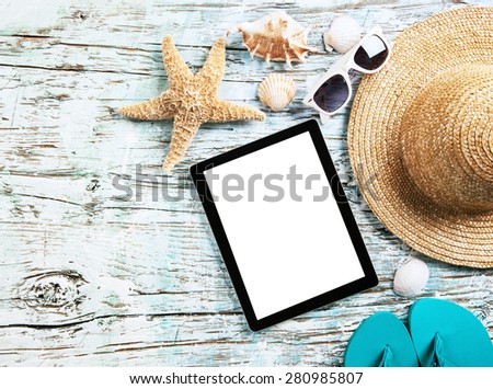 Top view of summer accessories and blank tablet on wooden planks