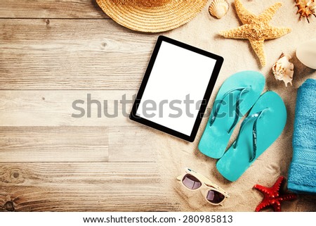Top view of summer accessories and blank tablet on wooden planks