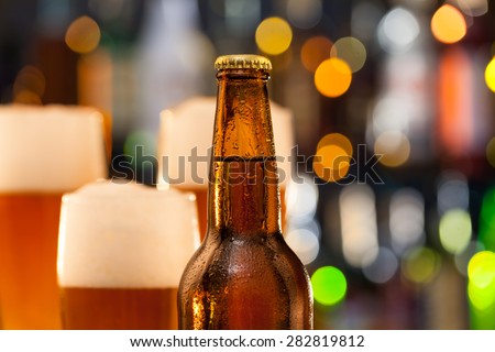 Bottle of beer with blur jugs on background