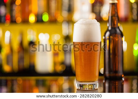 Jug of beer with bottle, placed on bar counter with copy space