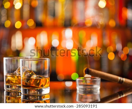 Whiskey drinks on bar counter with blur bottles on background