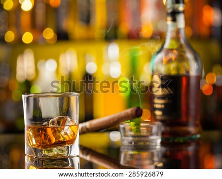 Whiskey drink with smoking cigar, served on bar counter