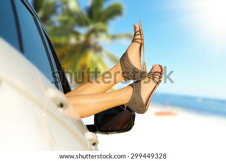 Summer road trip car vacation concept. Woman legs out the windows in car. Conceptual freedom, travel and holidays image with copy space.