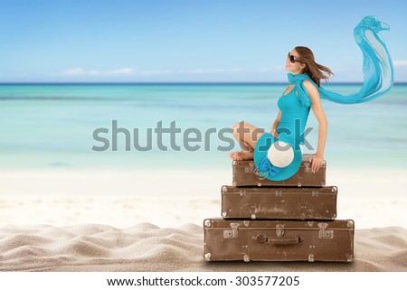 Pretty woman sitting on retro suitcases on beach. Concept of traveling
