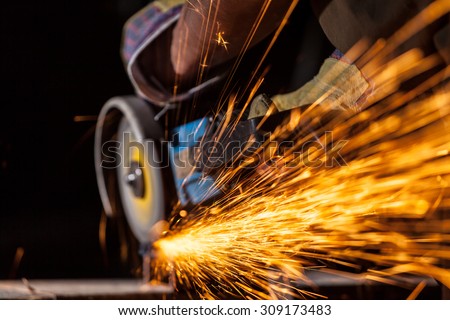 Close-up of worker cutting metal with grinder. Sparks while grinding iron. Low depth of focus
