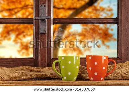Vintage wooden window overlook autumn trees, shot from cottage interior with cups of tea