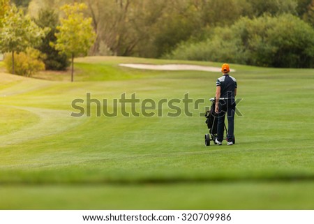 Golf man player holding trolley with clubs