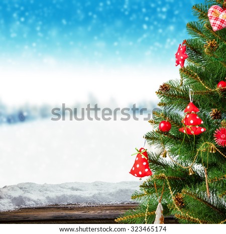 Winter background with Christmas tree and blur landscape. Empty wooden planks on foreground. Copyspace for text