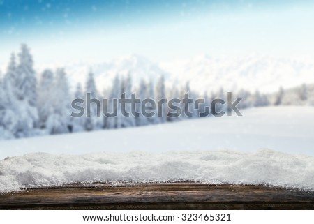 Winter background with pile of snow and blur landscape. Empty wooden planks on foreground. Copyspace for text
