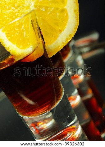 Glasses of shots with citrus slice on black background