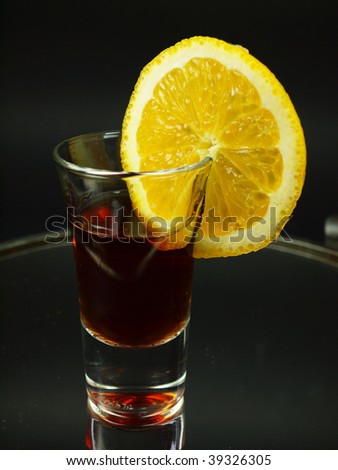 Glass of shot with citrus slice on black background