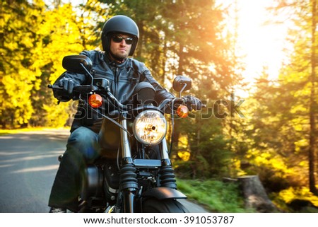 Motorcyclist riding a chopper on a road in morning sun